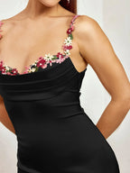 Robe longue ajustée sans manches en tissu léger avec ornements floraux délicats, idéale pour une soirée élégante.