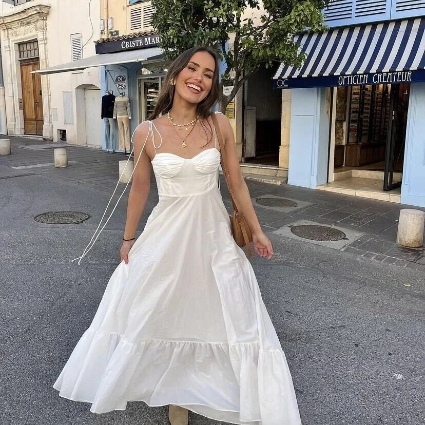 Robe longue blanche à bretelles fines, en coton léger, avec buste froncé et jupe fluide, idéale pour l'été.