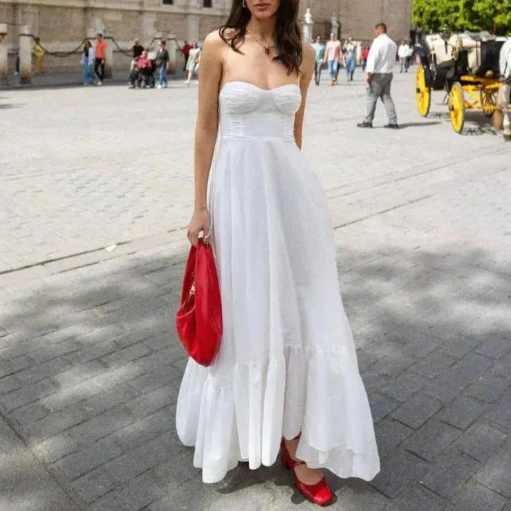 Robe longue blanche à bretelles fines, en coton léger, avec buste froncé et coupe estivale idéale pour des journées chaudes.