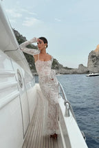 Robe longue blanche en dentelle, manches longues, texture délicate, design élégant, idéale pour mariage ou cocktail.