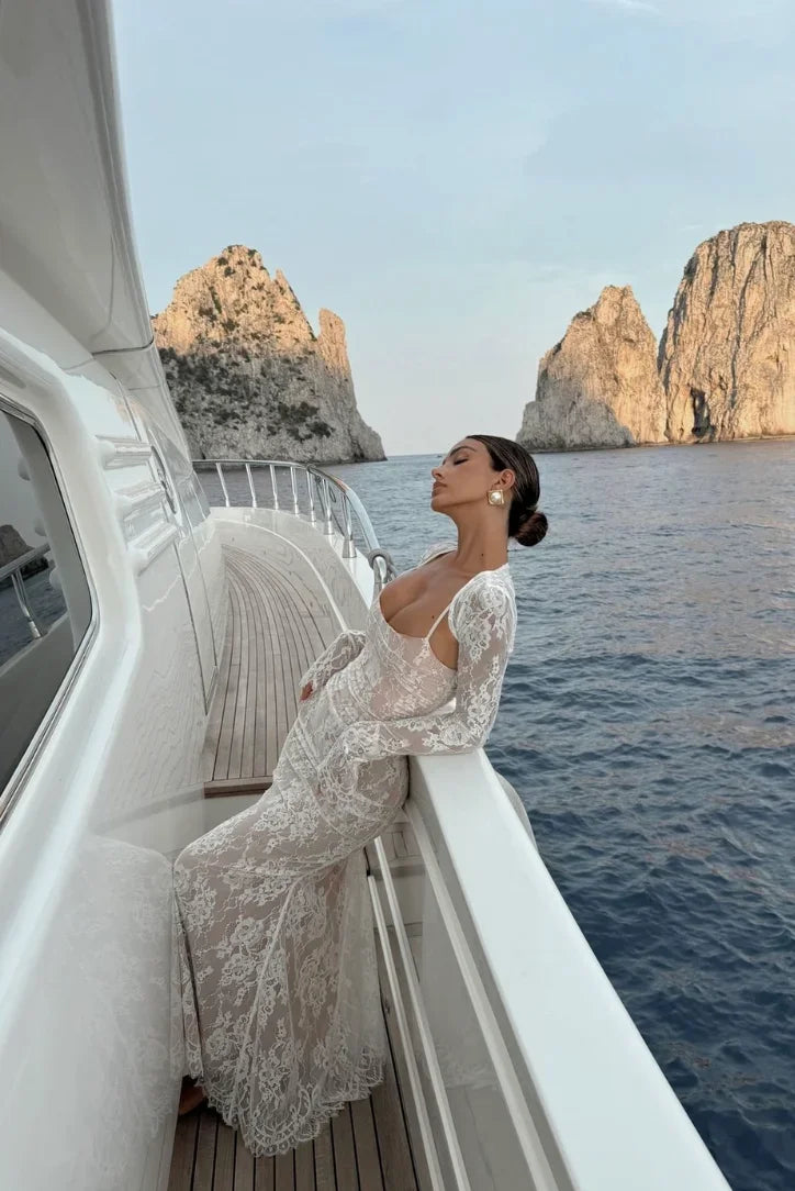 Robe longue en dentelle blanche, manches longues, silhouette fluide, idéale pour mariage ou cocktail.