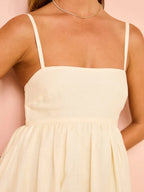 Robe longue blanche en coton, motifs floraux colorés, ourlet délicat et bretelles fines, idéale pour l'été.