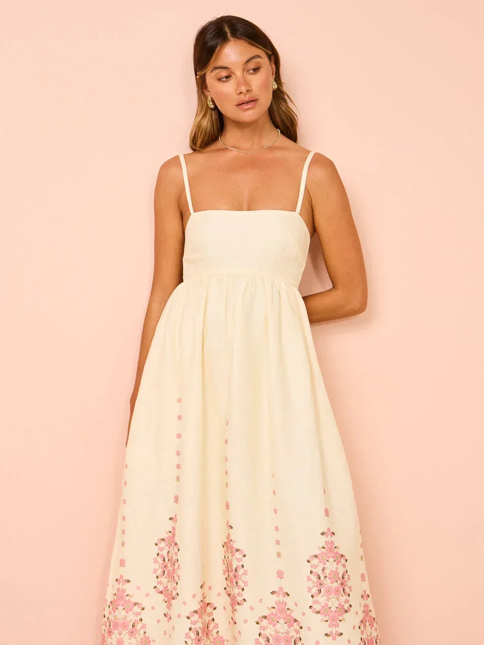 Robe longue blanche en coton, ornée de motifs floraux et d'un ourlet détaillé, avec des bretelles fines idéale pour l'été.