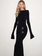 Robe longue noire en tissu léger, manches longues, avec embellissements délicats sur le côté pour une touche élégante.