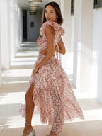 Robe longue rose en tissu léger, décolleté en V, volants et motifs floraux, idéale pour les soirées d'été.