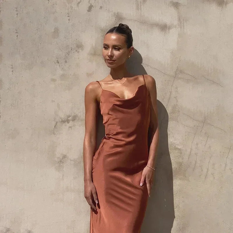 Robe longue sans manches en satin, col bénitier, disponible en plusieurs couleurs, avec une coupe fluide et élégante.
