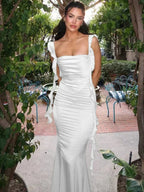 Robe longue en satin avec col bénitier, dos ouvert et liens latéraux, offrant une allure élégante et fluide.