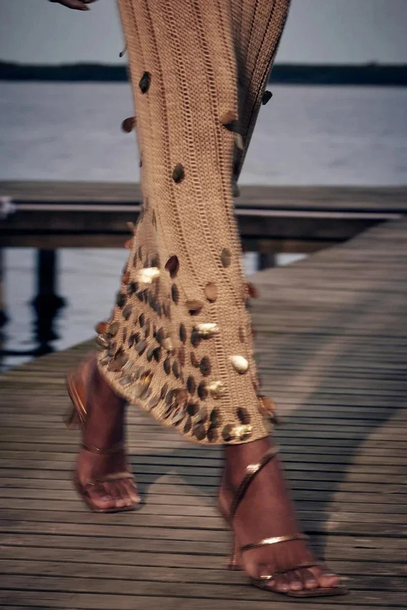 Robe longue dorée transparente en sequins, manches longues, décolleté plongeant, parfaite pour une soirée élégante.