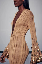 Robe longue transparente dorée à sequins, manches longues, décolleté plongeant, idéale pour les soirées élégantes.