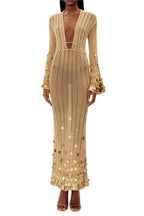 Robe longue transparente en tissu doré avec sequins, manches longues et décolleté plongeant, idéale pour les soirées.