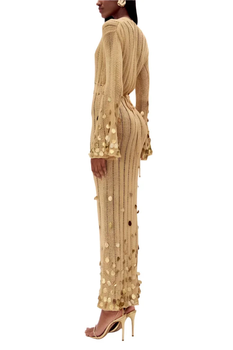 Robe longue dorée avec sequins, manches longues et décolleté plongeant, parfaite pour une soirée élégante.