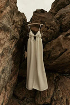 Robe longue beige en tissu doux, ornée de détails floraux et d'une fente élégante, parfaite pour les soirées.