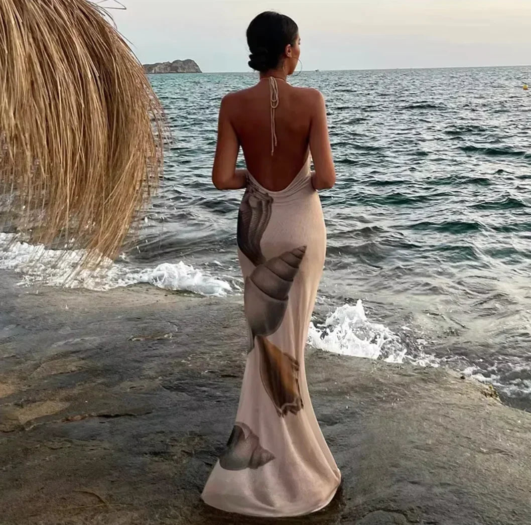 Robe longue beige sans manches avec imprimé coquillage, col haut et coupe ajustée en tissu léger pour soirées élégantes.