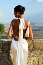 Robe longue blanche en tissu léger, dos ouvert avec des détails en perles, idéale pour une soirée d'été élégante.