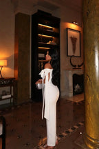 Robe longue blanche en tissu léger, épaules dénudées, coupe ajustée, détail nœud, parfaite pour les soirées élégantes.