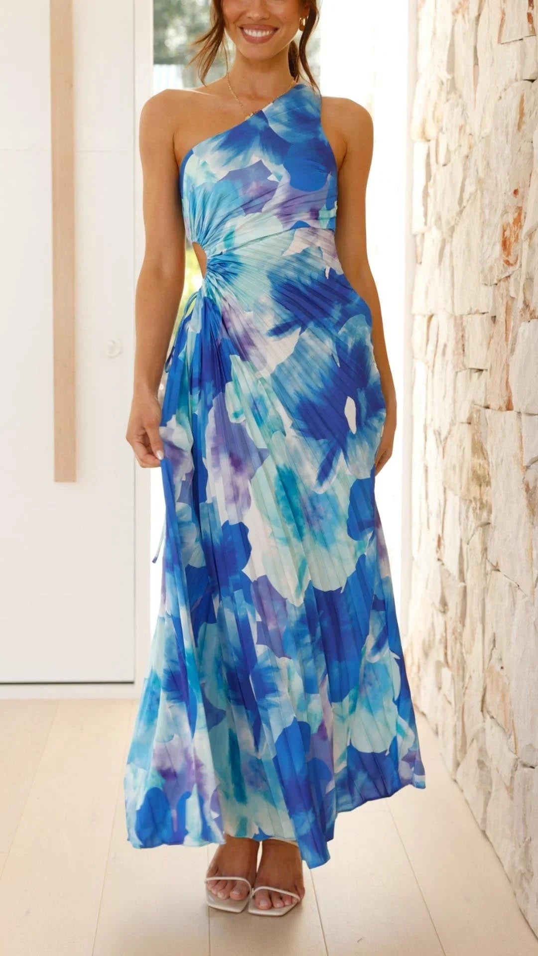 Robe longue asymétrique à une épaule en tissu léger, imprimé floral sur fond bleu, parfaite pour les journées d'été.