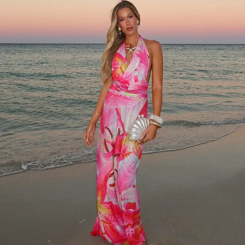 Robe longue dos nu rose à nouer, col halter, en tissu léger, imprimée avec motifs estivaux, idéale pour la plage.