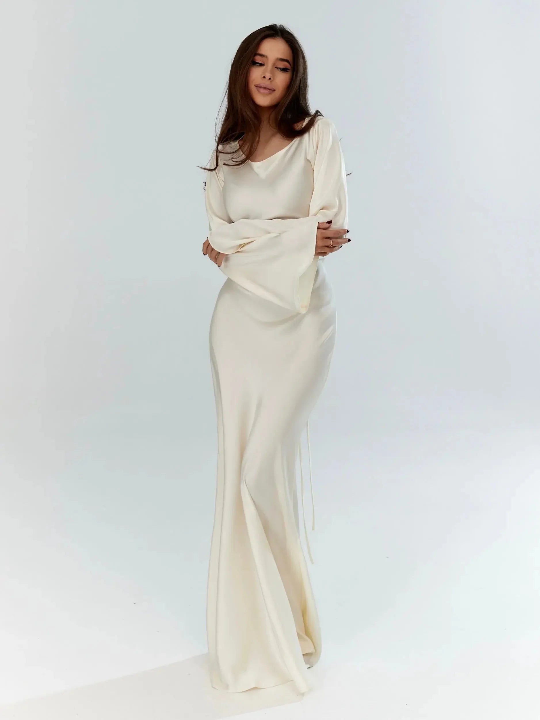 Robe maxi blanche à manches longues, en tissu doux, silhouette fluide pour invité de mariage.