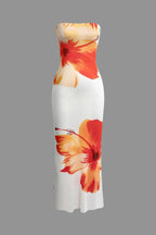 Robe longue fleurie sans bretelles, blanche et orange, en tissu léger idéal pour l'été, avec un design floral vibrant.