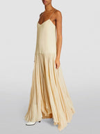 Robe longue ivoire sans manches, plissée avec bretelles fines, idéale pour des soirées d'été. Matière légère et fluide.