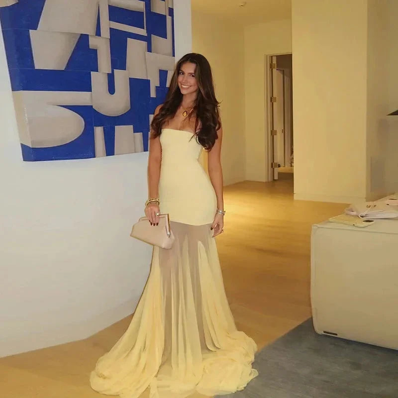 Robe longue jaune sans bretelles, fluide avec jupe transparente, idéale pour des occasions spéciales. Couture délicate.