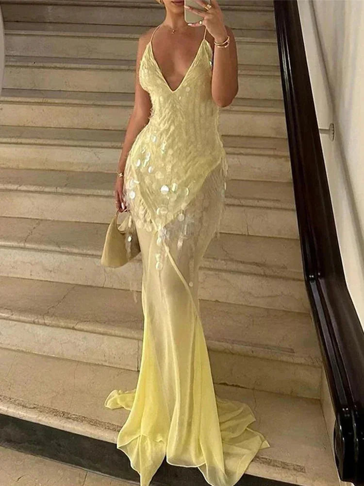 Robe longue jaune en tissu transparent, sequins scintillants, dos nu croisé et col en V pour soirées estivales.