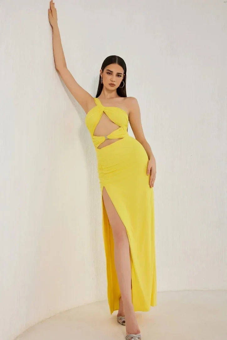 Robe longue jaune à une épaule en tissu léger, avec découpe sur le côté et fente haute pour une allure estivale élégante.