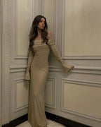 Robe longue longue en tissu brillant, épaules dénudées, manches longues, avec détails scintillants. Idéale pour les soirées.