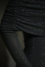 Robe longue longue scintillante avec épaules dénudées, manches longues et détails brillants en tissu léger et fluide.