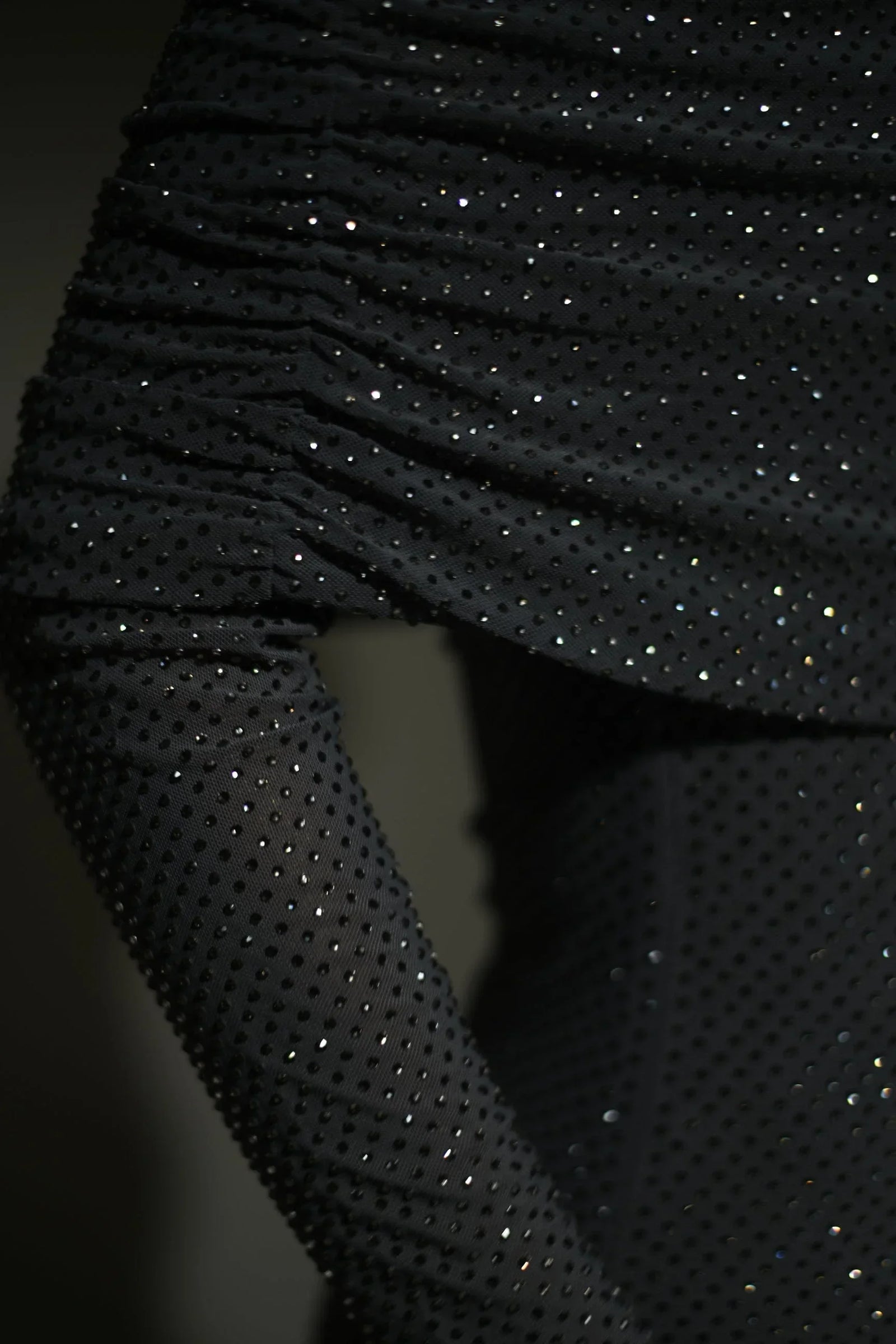 Robe longue longue scintillante avec épaules dénudées, manches longues et détails brillants en tissu léger et fluide.