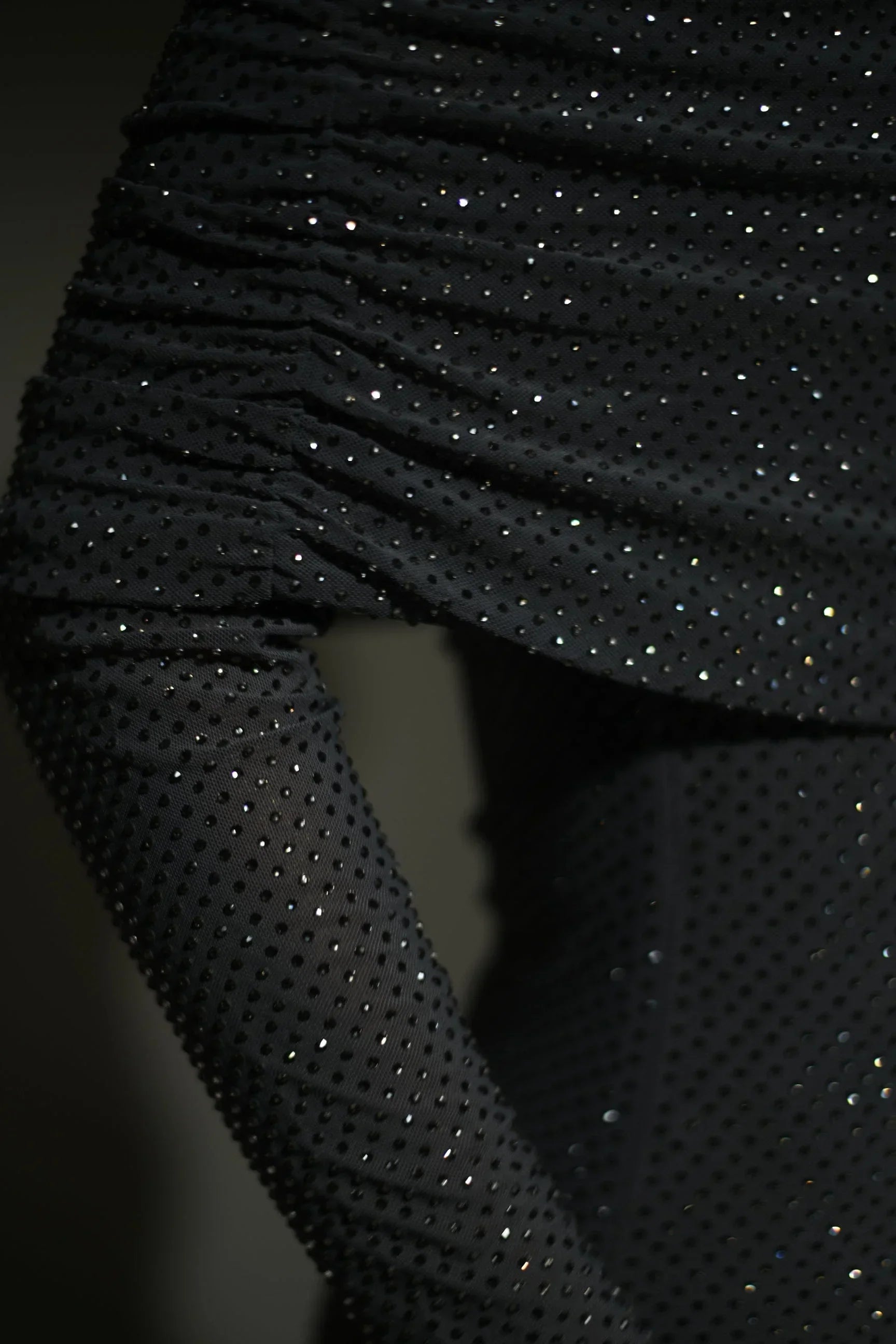 Robe longue longue scintillante avec épaules dénudées, manches longues et détails brillants en tissu léger et fluide.