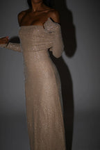 Robe longue longue scintillante avec épaules dénudées, manches longues et détails brillants, en tissu fluide et léger.