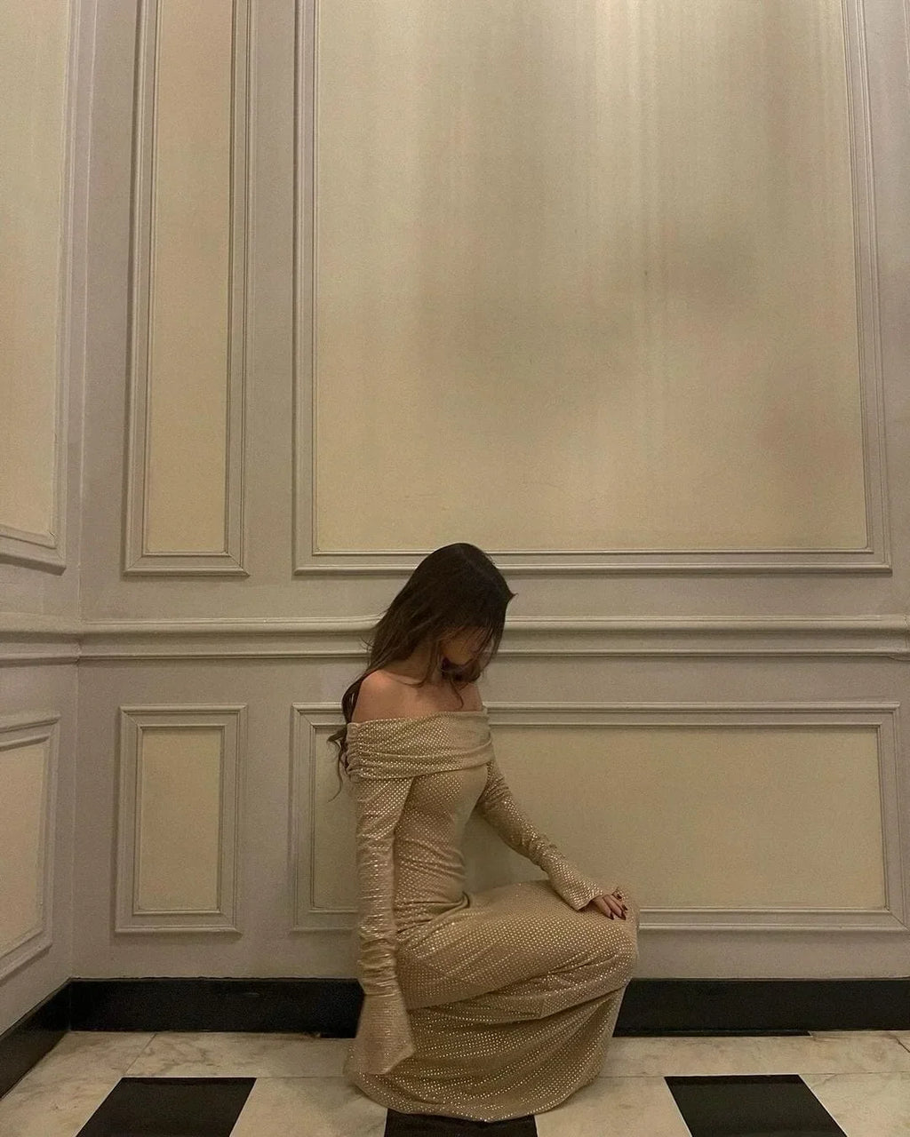 Robe longue longue en tissu scintillant, épaules dénudées, manches longues, avec accents brillants pour un look élégant.