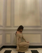 Robe longue longue en tissu scintillant, épaules dénudées, manches longues, avec accents brillants pour un look élégant.