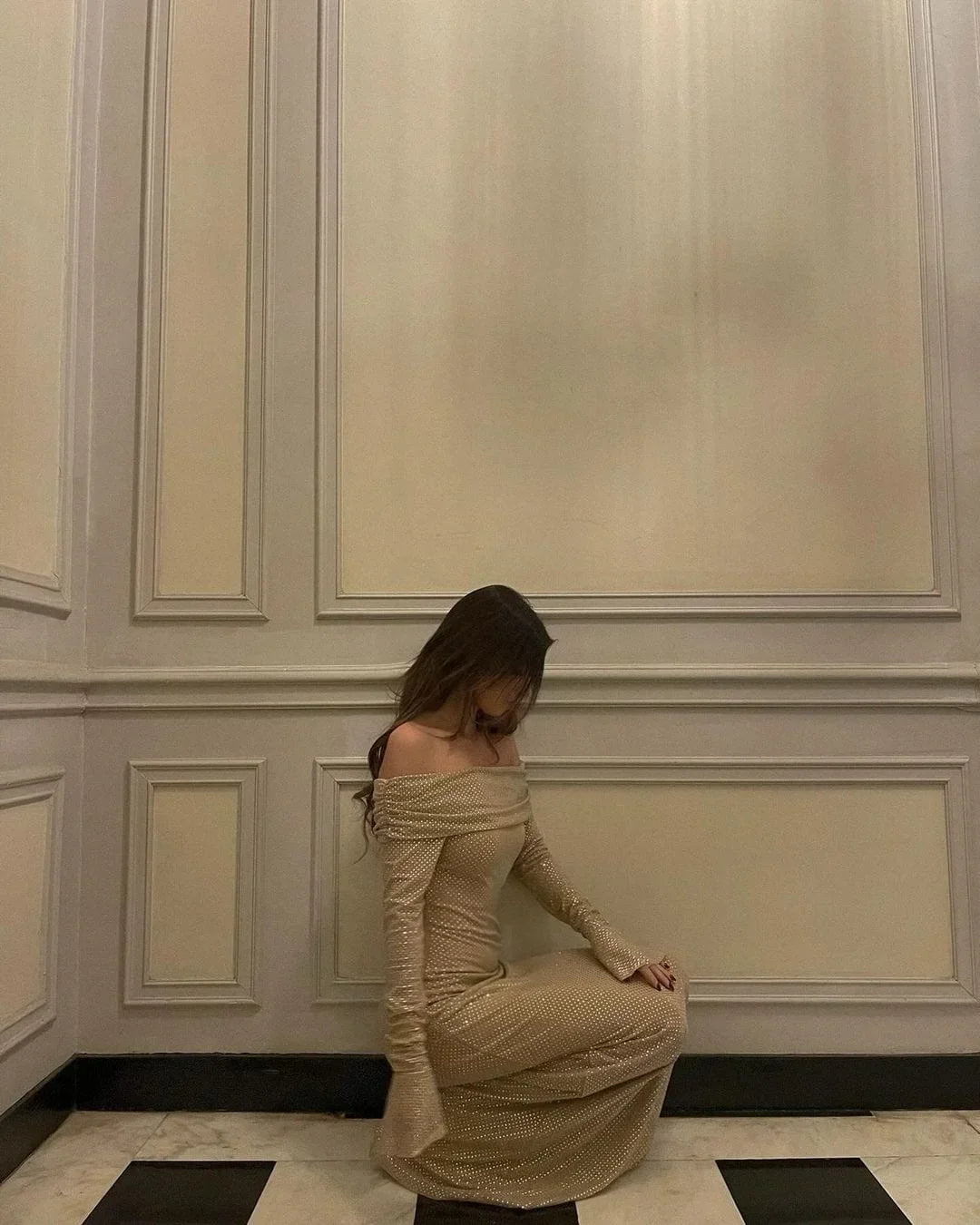 Robe longue longue en tissu scintillant, épaules dénudées, manches longues, avec accents brillants pour un look élégant.