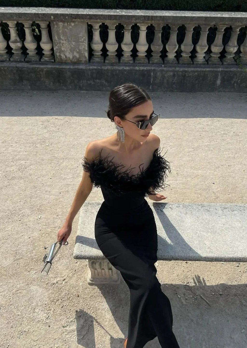 Robe longue noire sans bretelles avec une bordure en plumes, conçue en tissu léger et fluide, parfaite pour les soirées.