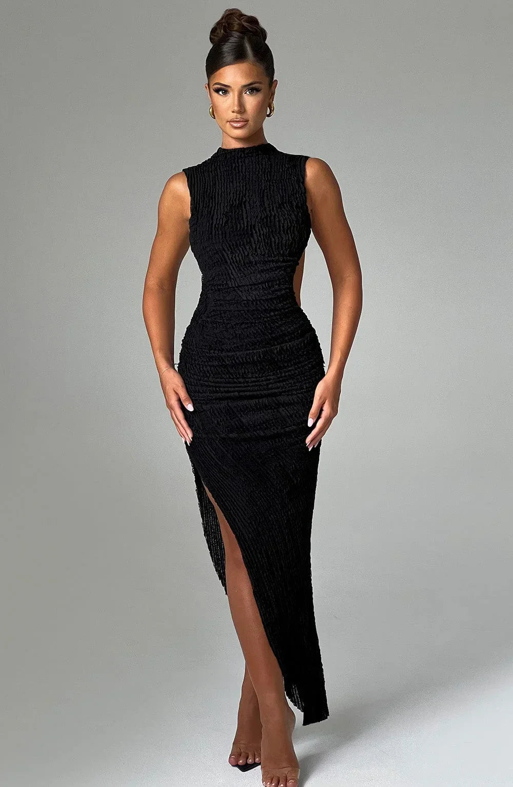 Robe longue noire sans manches, coupe ajustée et fendue, en tissu texturé avec découpe latérale pour une silhouette élégante.