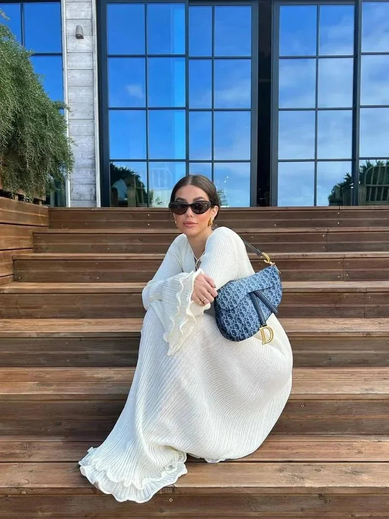 Robe longue plissée avec manches longues évasées et col rond, en tissu texturé, parfaite pour une soirée élégante.