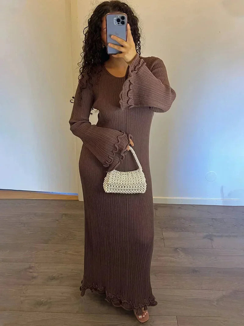 Robe longue plissée en tissu texturé, manches longues évasées, col rond, idéale pour des soirées élégantes.