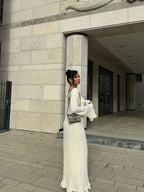 Robe longue plissée avec manches longues évasées, col rond et tissu texturé, parfaite pour une soirée élégante.