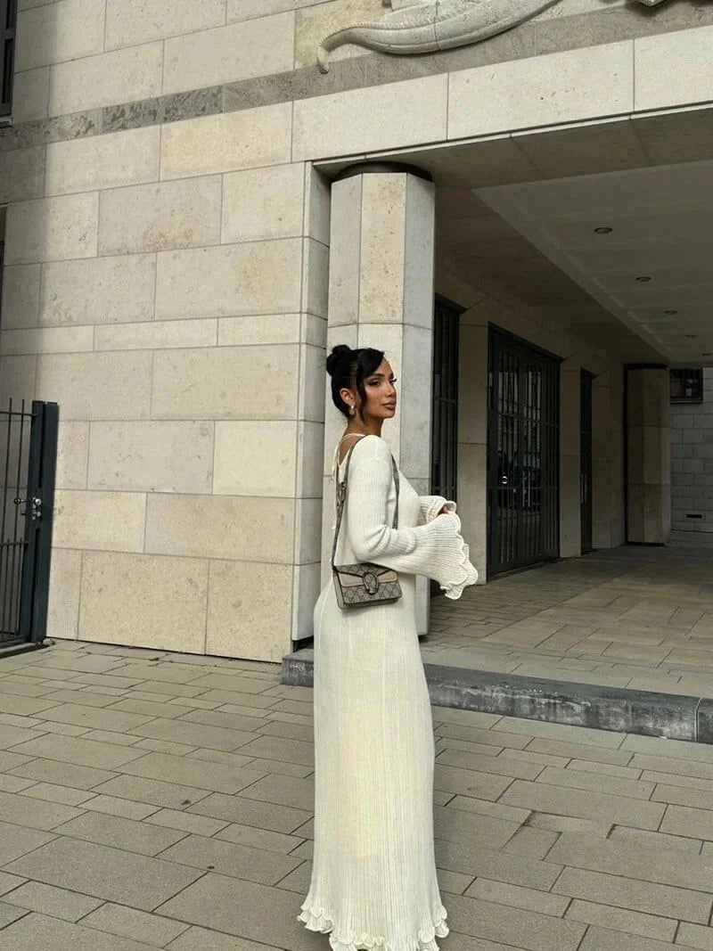 Robe longue plissée avec manches longues évasées, col rond et tissu texturé, parfaite pour une soirée élégante.