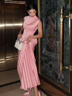 Robe longue plissée rose sans manches avec col asymétrique, en tissu léger et fluide, idéale pour les journées d'été.