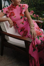 Robe longue rose avec motifs floraux, manches volantées et col haut, en tissu léger et fluide, parfaite pour l'été.