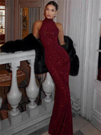 Robe longue rouge bordeaux à paillettes, col halter, coupe ajustée, idéale pour les soirées élégantes.