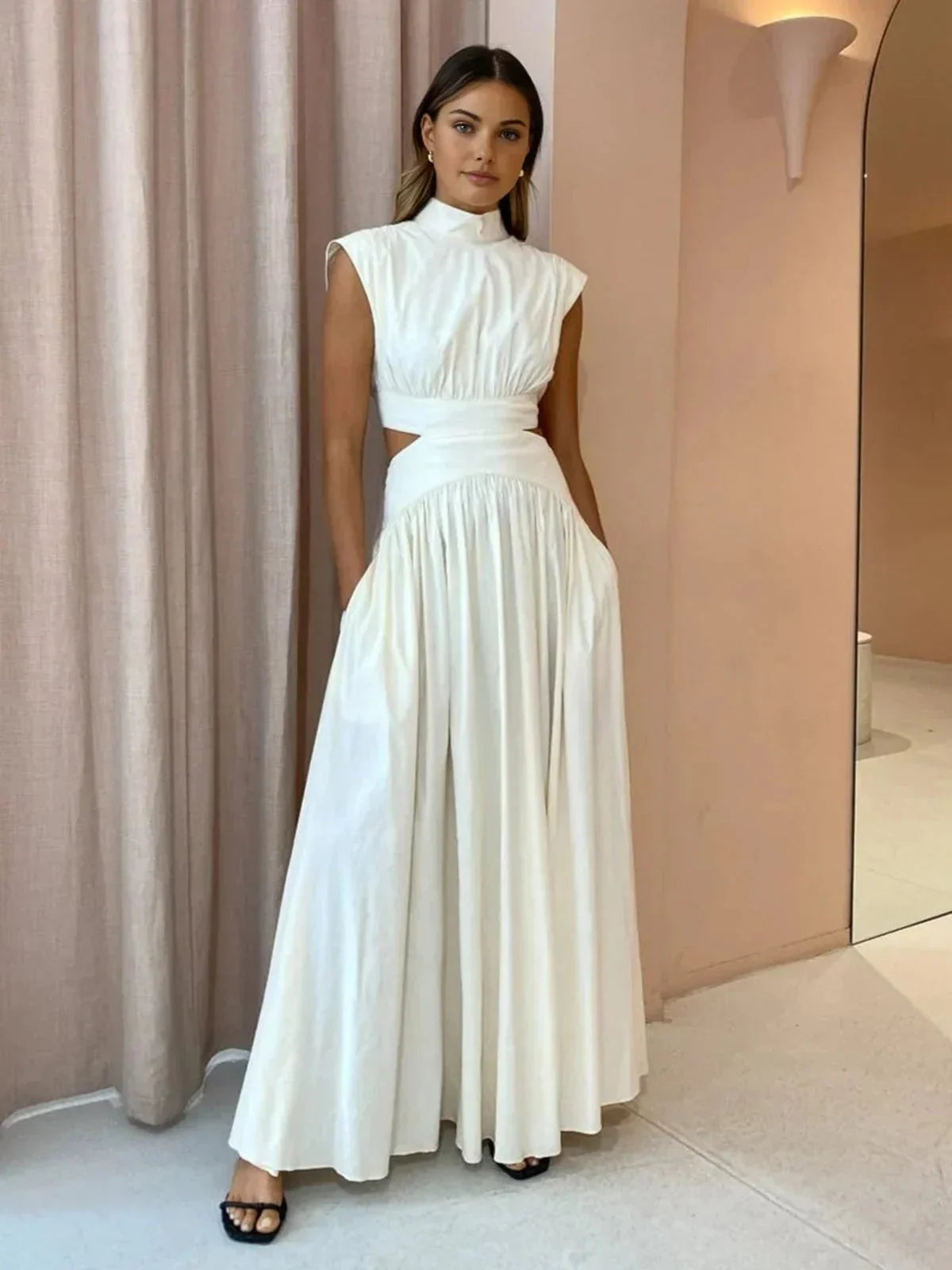 Robe longue sans manches en tissu léger, col montant, avec découpes élégantes, idéale pour une soirée d'été.