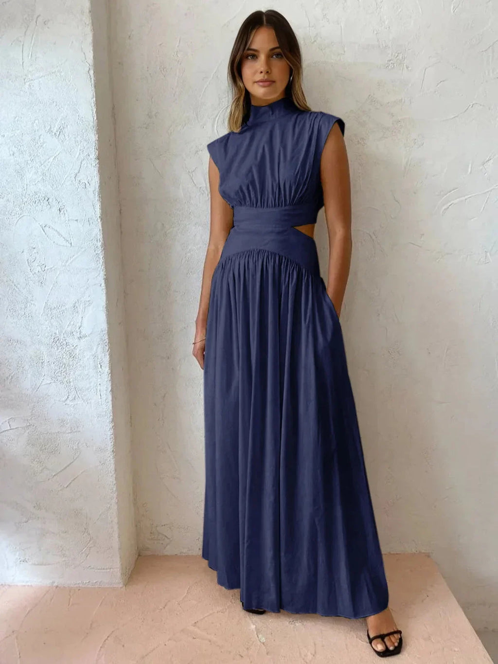 Robe longue sans manches en tissu léger, col montant, avec découpes sur les côtés, idéale pour une soirée estivale.