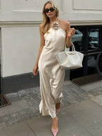 Robe longue satin ivoire avec dos nu et décoration rose, idéale pour un mariage, mettant en valeur une silhouette élégante.