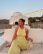 Robe longue sans manches en tissu scintillant, avec encolure plongeante et coupe fluide idéale pour les soirées.