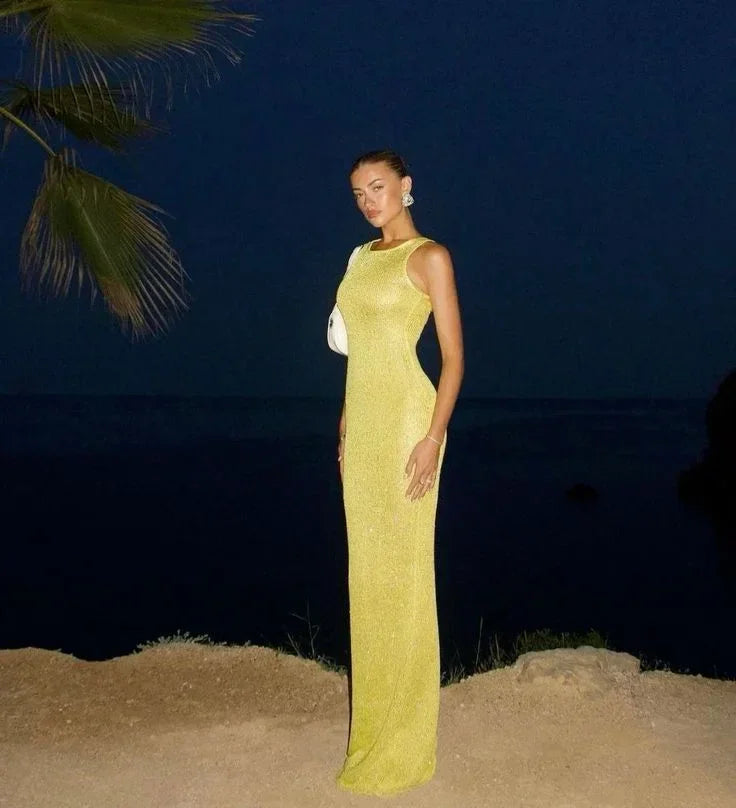 Robe longue sans manches en tissu scintillant, avec encolure plongeante, idéale pour les soirées élégantes.