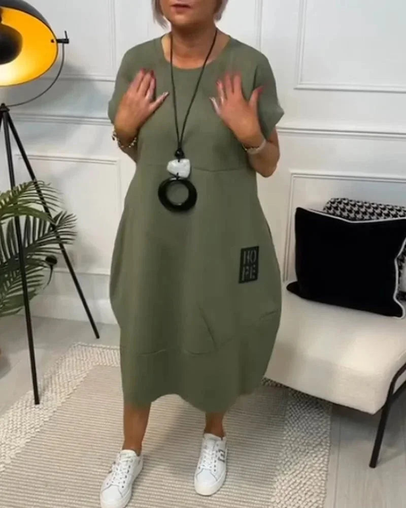 Robe midi ample en tissu fluide, manches courtes, design décontracté avec poches pour un usage quotidien toute saison.